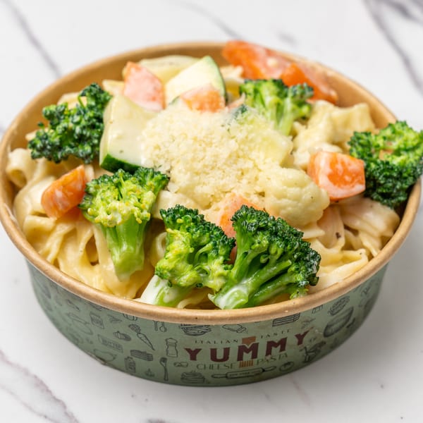 Creamy pasta with broccoli, carrots, and zucchini, topped with grated cheese in a Yummy Cheese Pasta bowl.